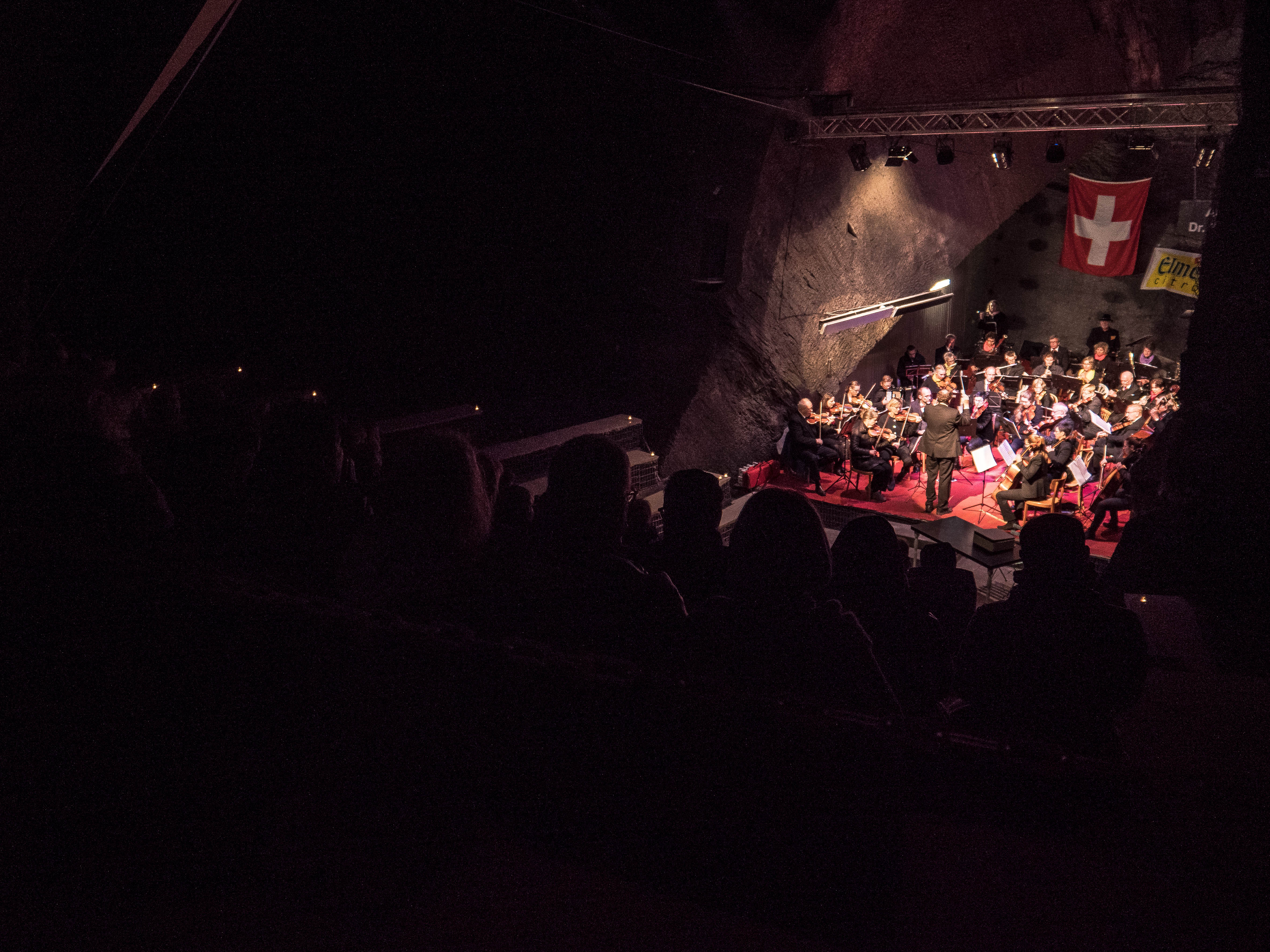 Orchester spielt im abgedunkelten Auditorium, Blick aus dem Publikum