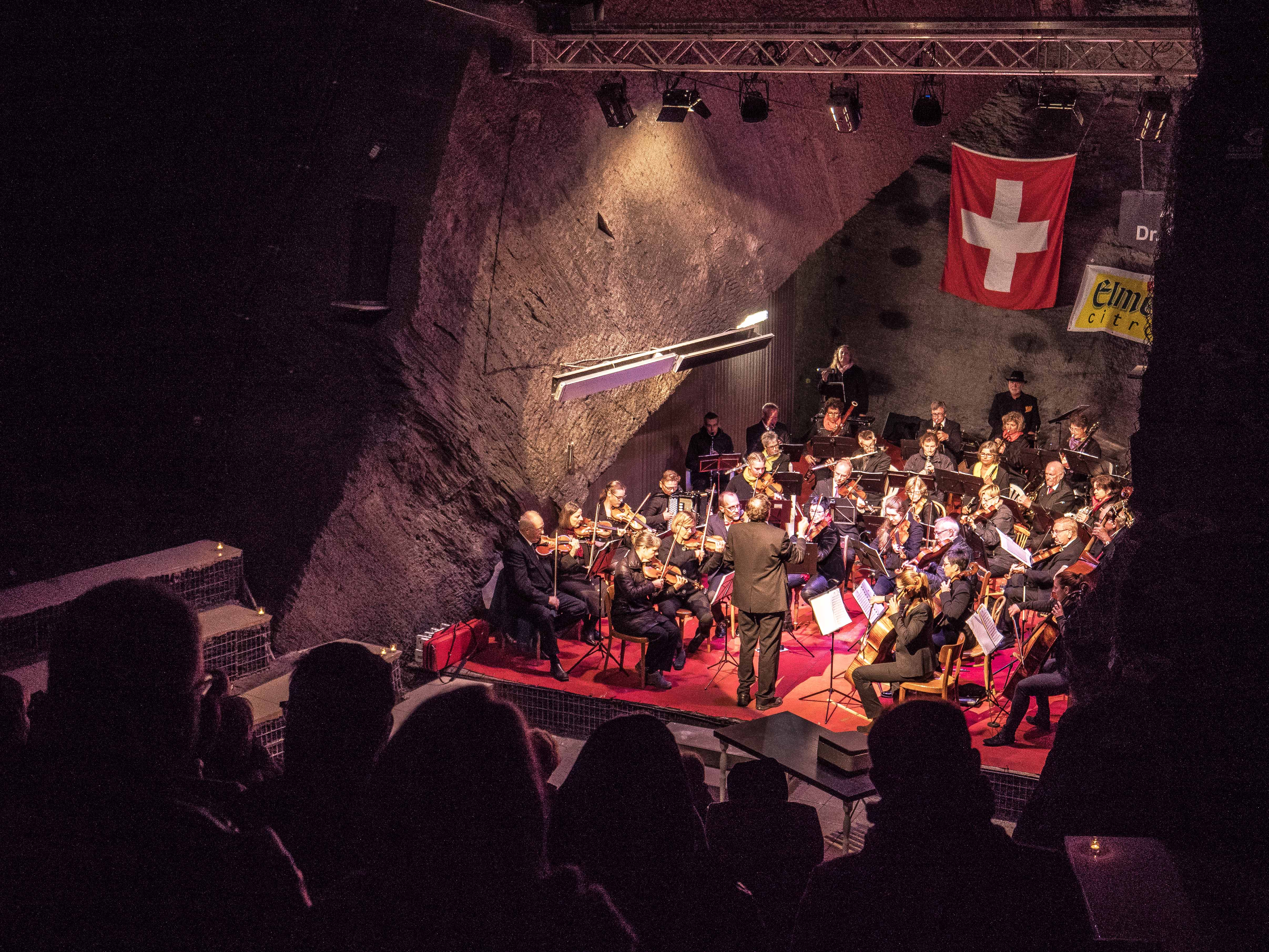 Orchester mit Dirigent im Auditorium des Landesplattenbergs, im Vordergrund das Publikum