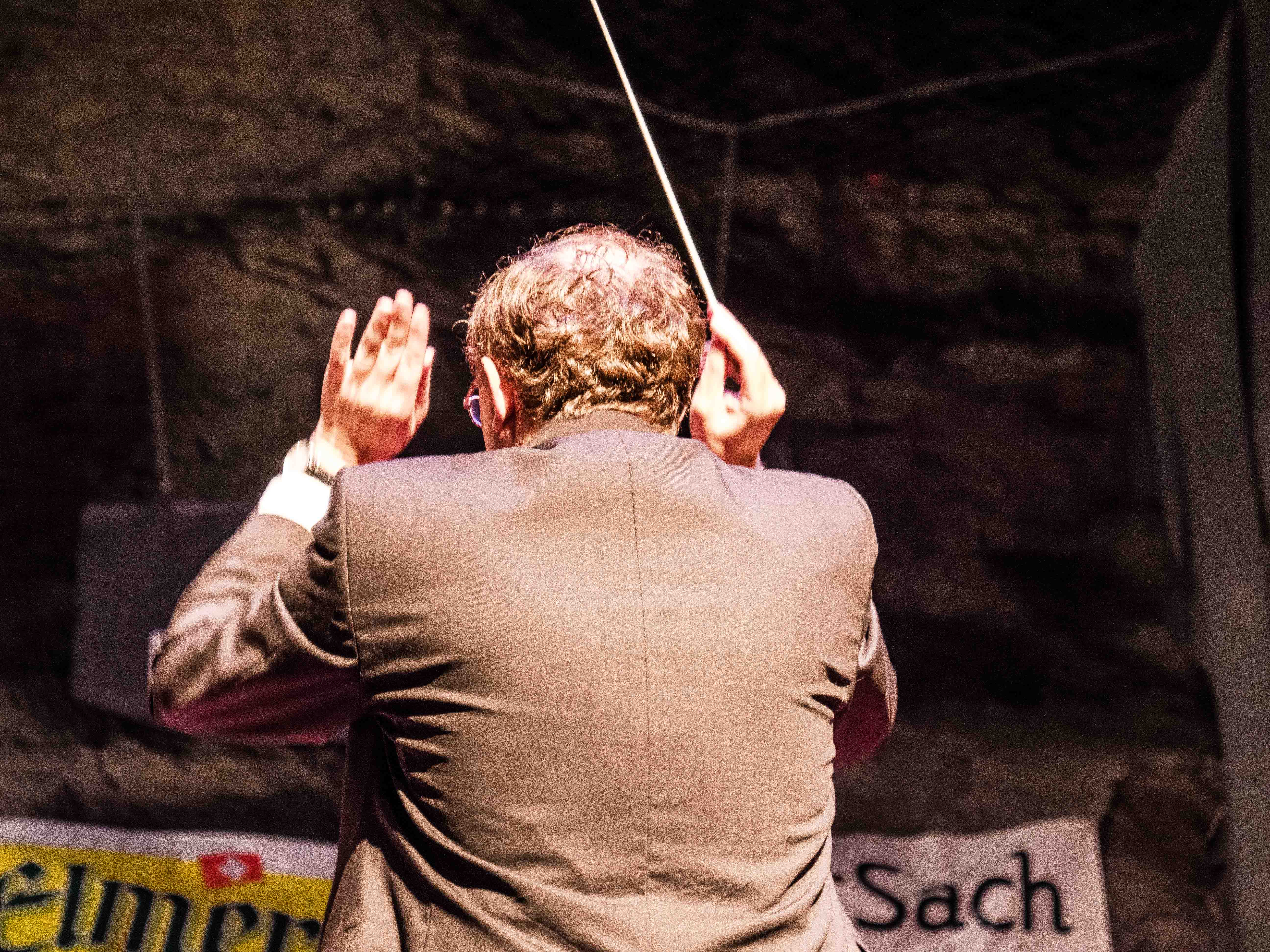 Dirigent von hinten mit erhobenen Armen beim Konzert im Landesplattenberg