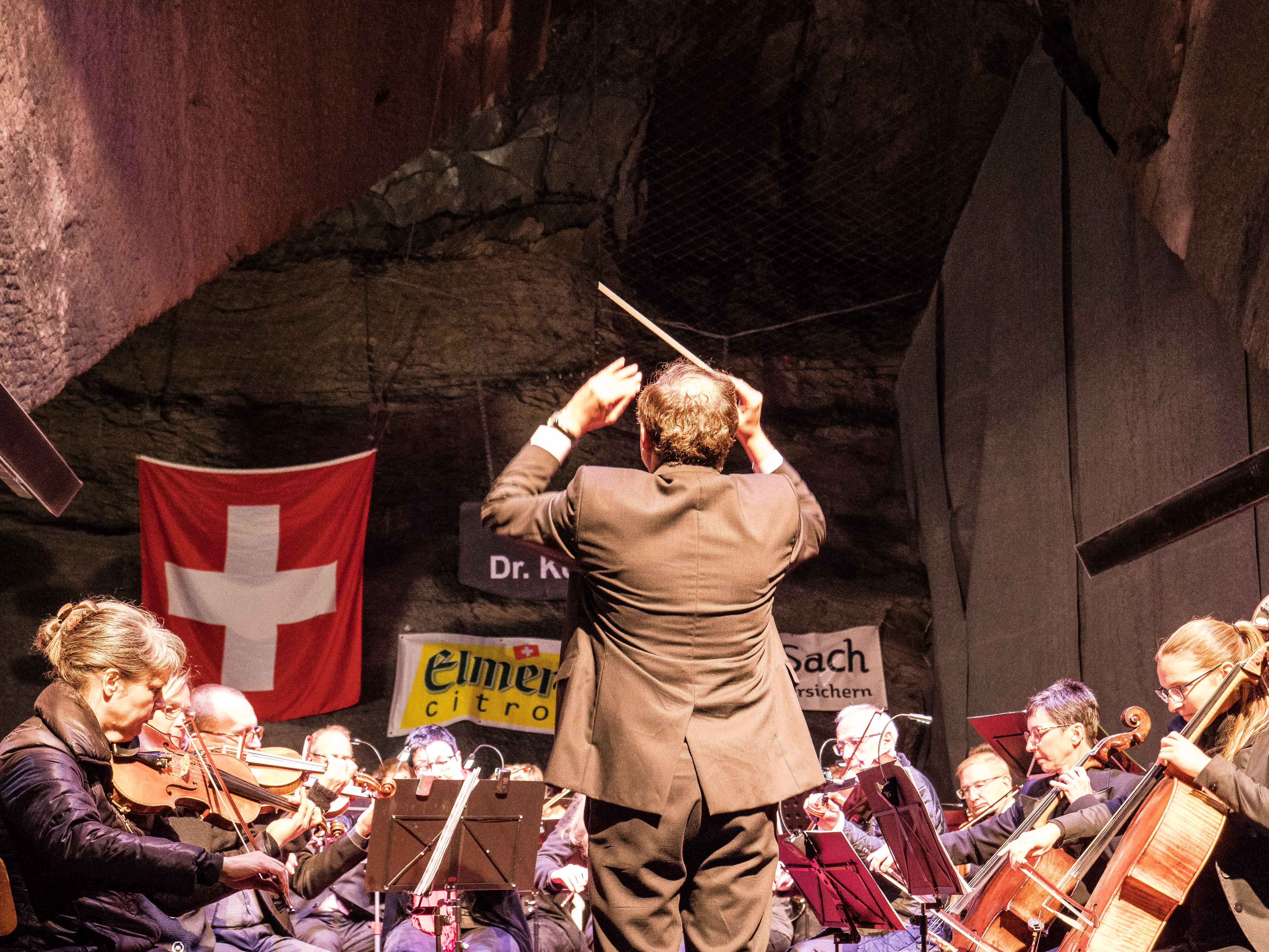 Dirigent und Orchester beim Konzert vor der Schweizer Fahne